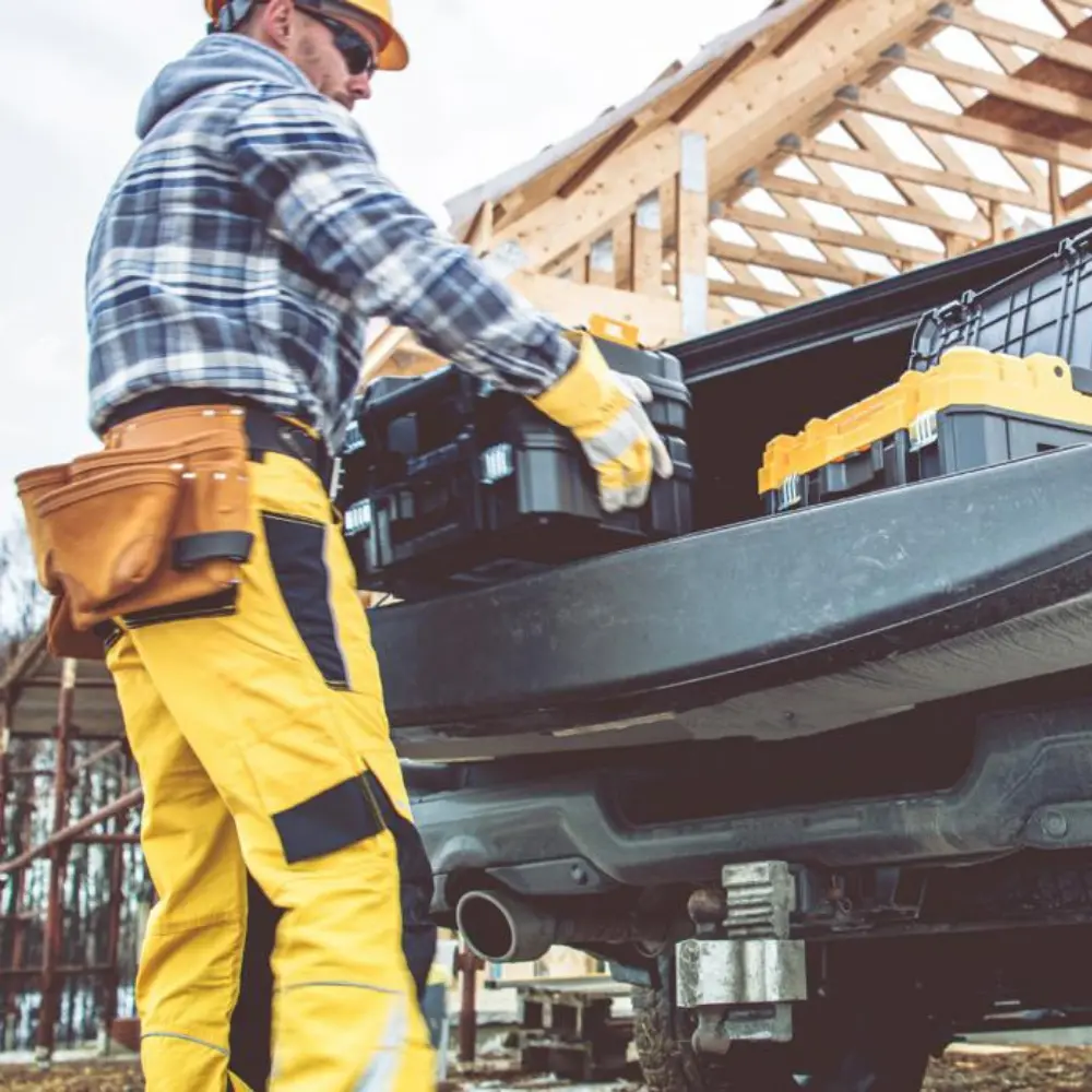 construction worker unloading toolboxes from a truck at a job site