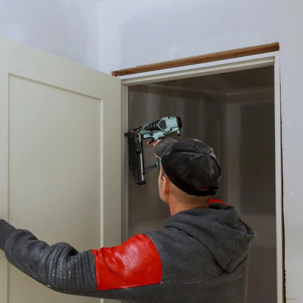 contractor using a nail gun to install interior door trim