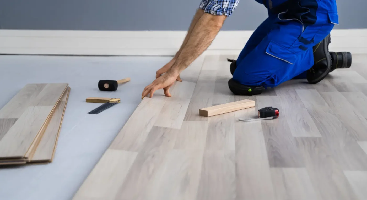 flooring contractor installing light wood laminate planks in a home