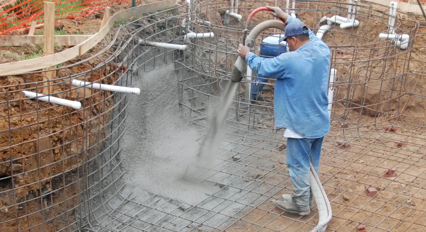 pool builder spraying concrete into a rebar pool frame